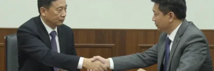 Un hombre con traje dándose la mano a sí mismo sobre una mesa de reuniones
