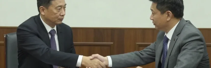 Un hombre con traje dándose la mano a sí mismo sobre una mesa de reuniones